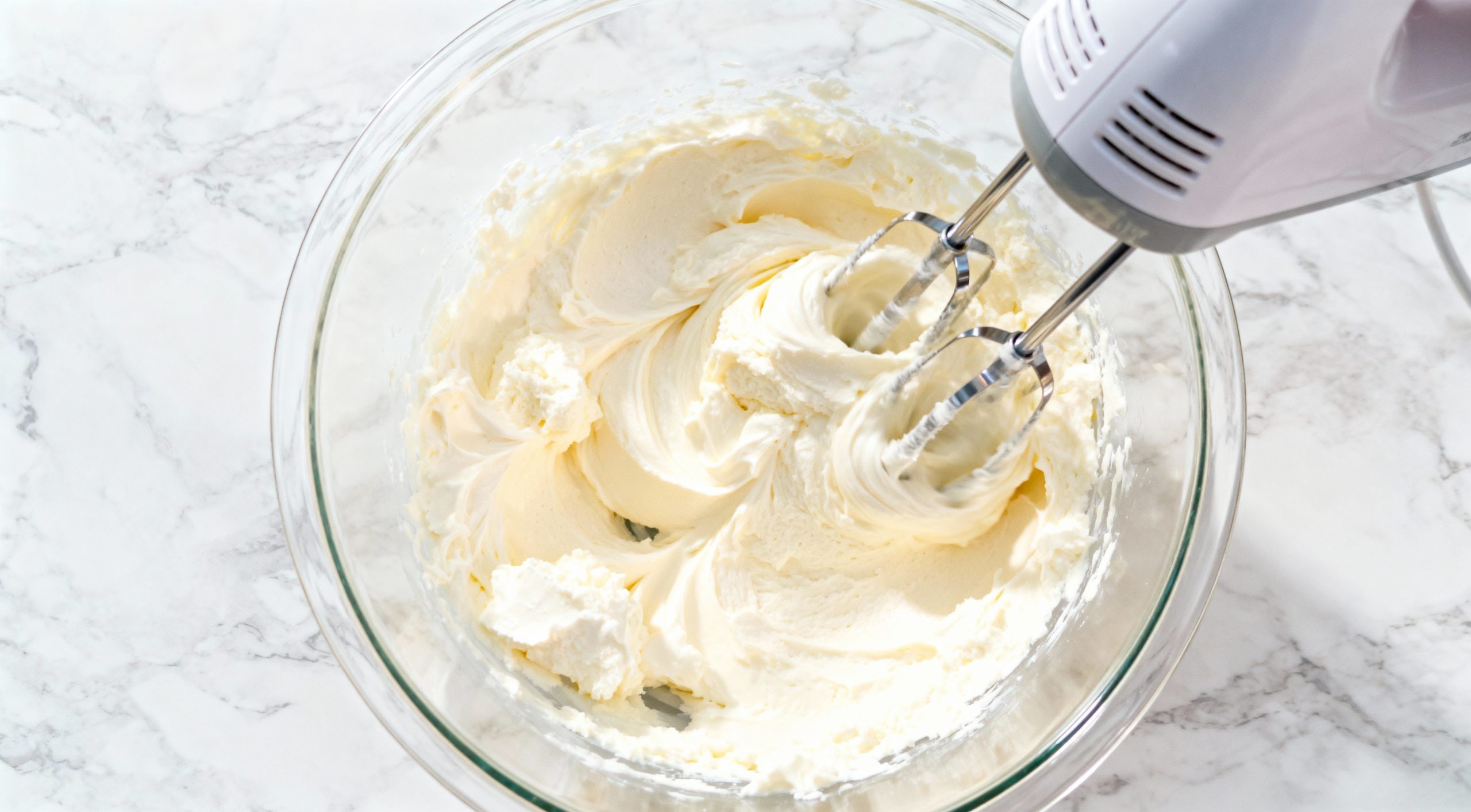 Blending cream cheese and ricotta in a bowl with a mixer for Italian cream cheese and ricotta cheesecake.