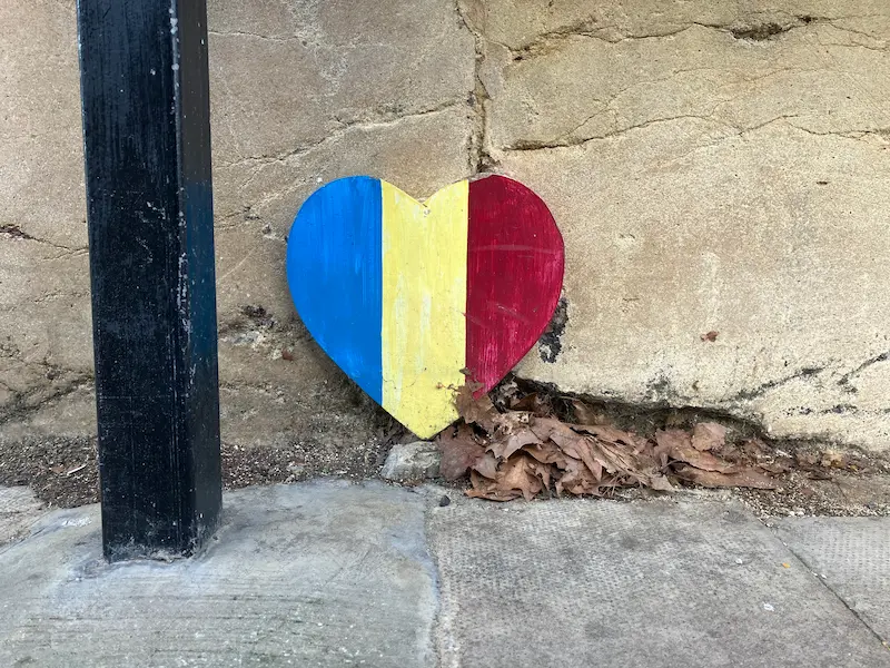 A wooden heart, painted with the flag of Romania, affixed to a wall in Oxford