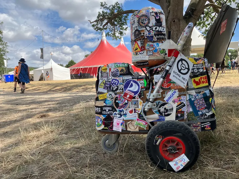 A small wheeled robot made mostly of speakers, completely covered in stickers. The beloved World O Techno.