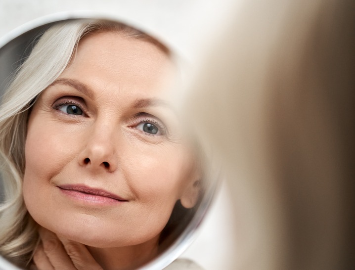 Mature woman with smooth skin looking at reflection
